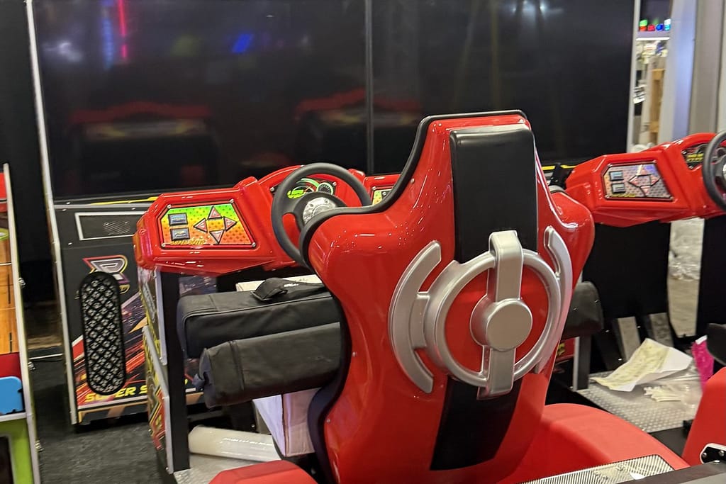 Κόκκινο καθιστό racing arcade simulator με τιμόνι και οθόνη, σε περίπτερο της IAAPA Expo Europe 2025