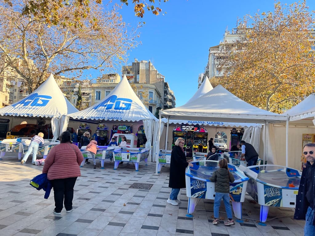Παιδιά παίζουν air hockey μπροστά στις τέντες AdamsGames στην Πλατεία Αριστοτέλους