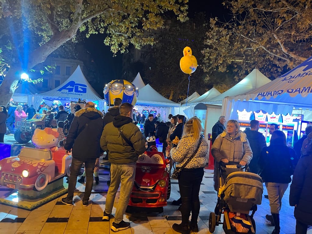 Νυχτερινή λήψη με κόσμο γύρω από τα φωτισμένα μηχανήματα της AdamsGames στην Πλατεία Αριστοτέλους
