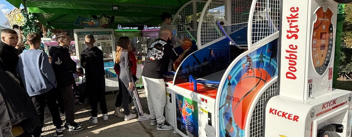 Πράσινη τέντα σε πλακόστρωτη πλατεία με μπασκέτες arcade και μηχάνημα σουτ, Δεκέμβριος 2024