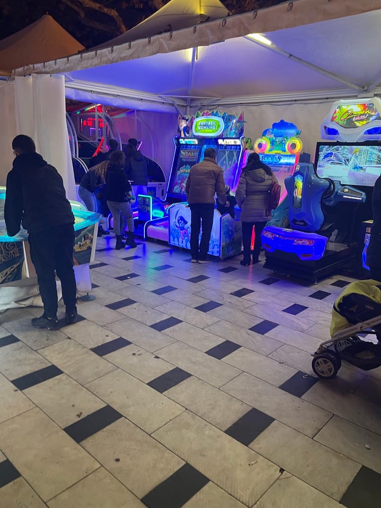 Επισκέπτες παίζουν σε arcade μηχανήματα μέσα σε τέντα με μπλε φωτισμό στη Θεσσαλονίκη